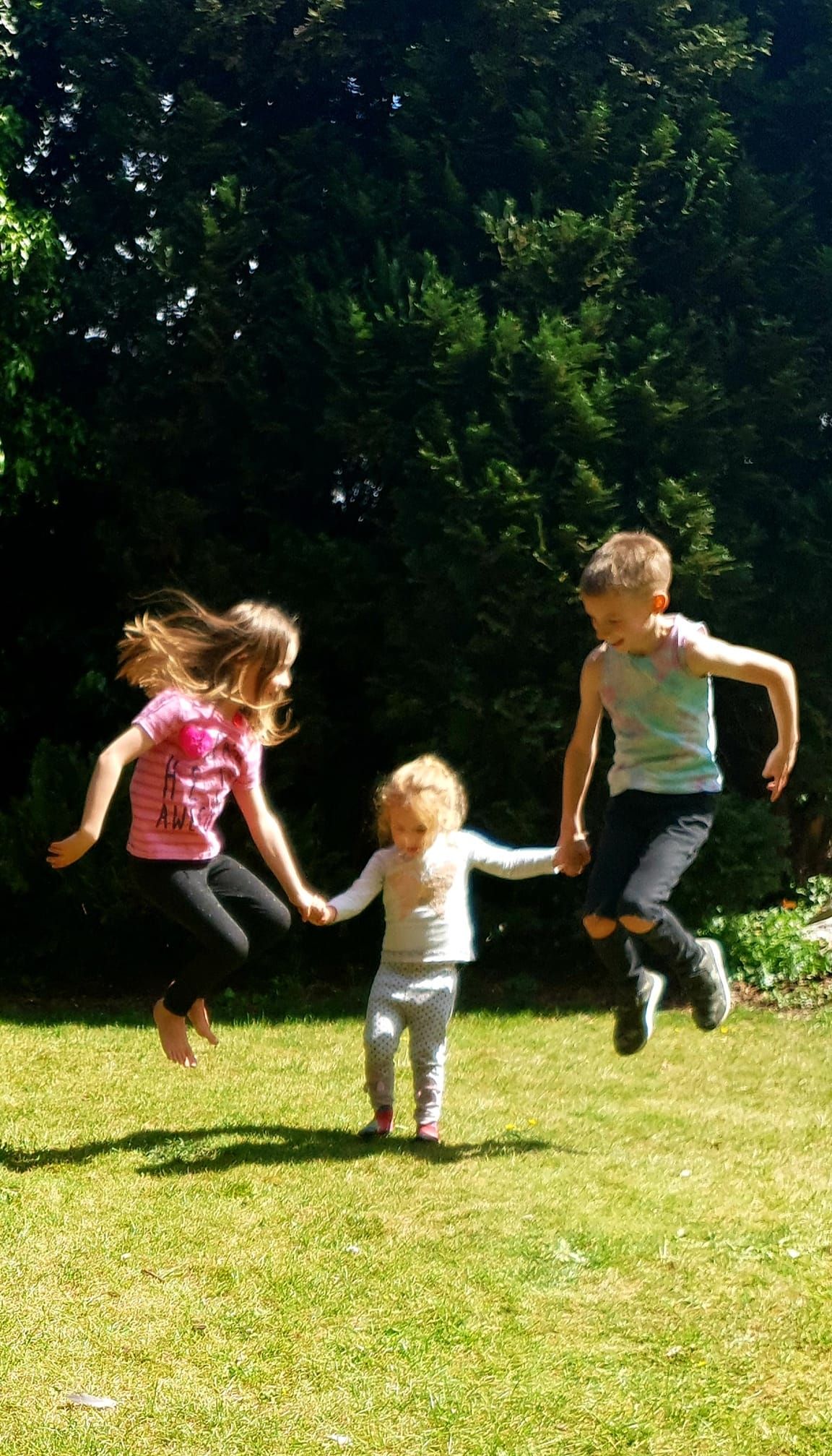 People jumping and playing together on sunny grass lawn.