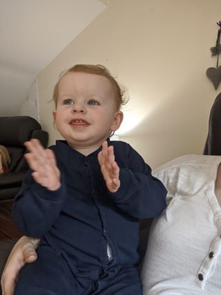Young child in navy blue outfit clapping hands with joyful expression.