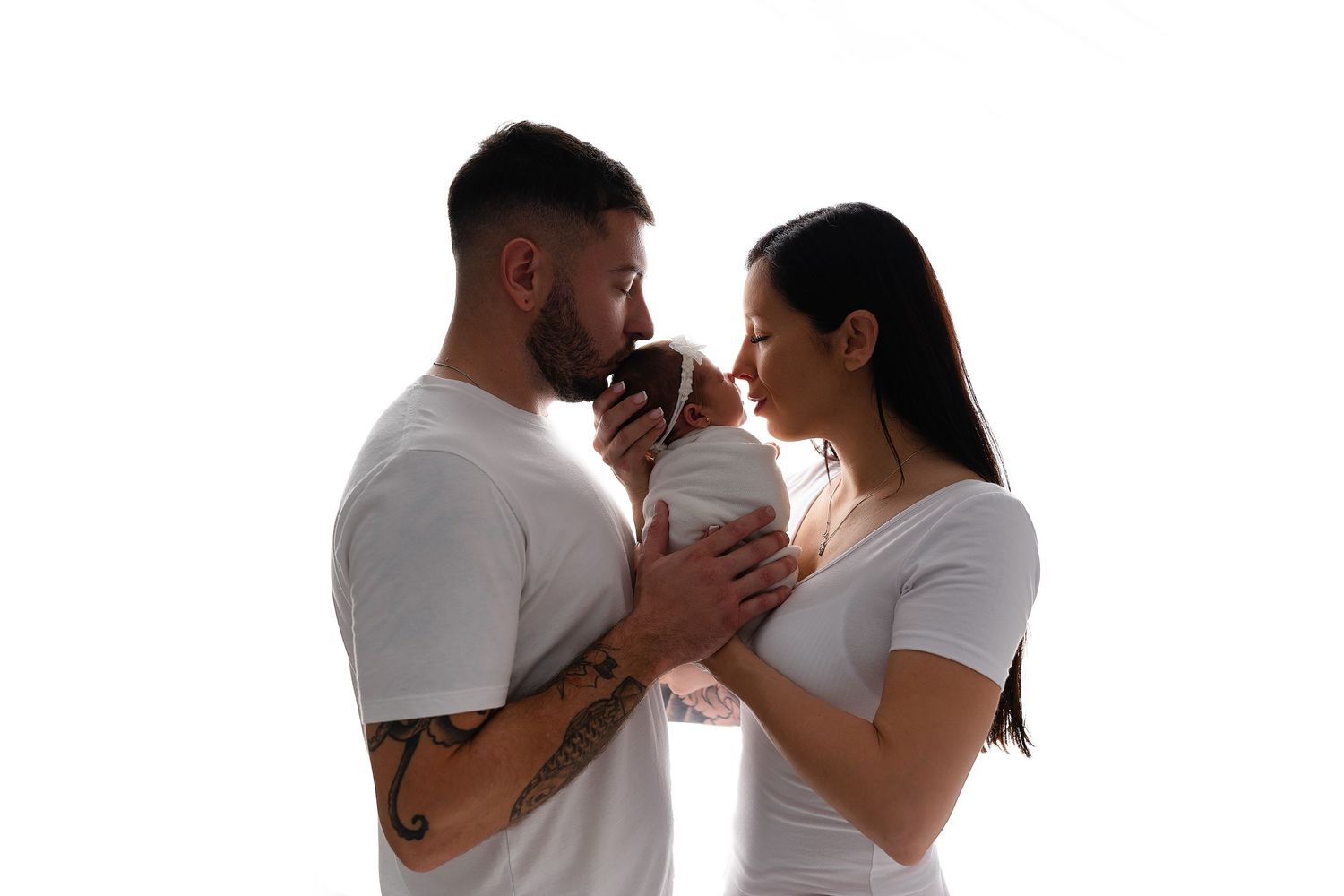 A couple in white t-shirts holds and gazes at each other against a white background.