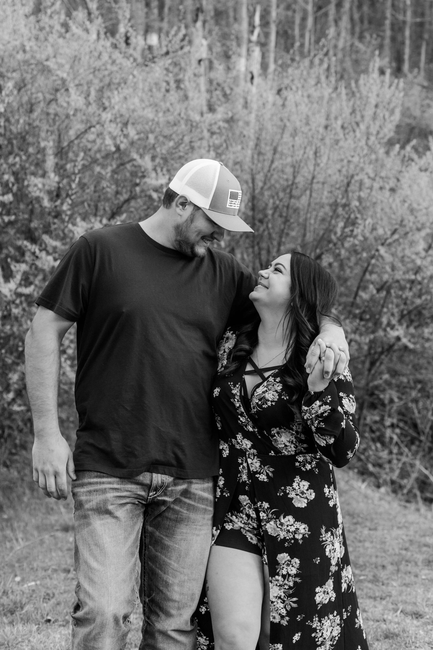 Black and white photo of a couple sharing a joyful moment outdoors.