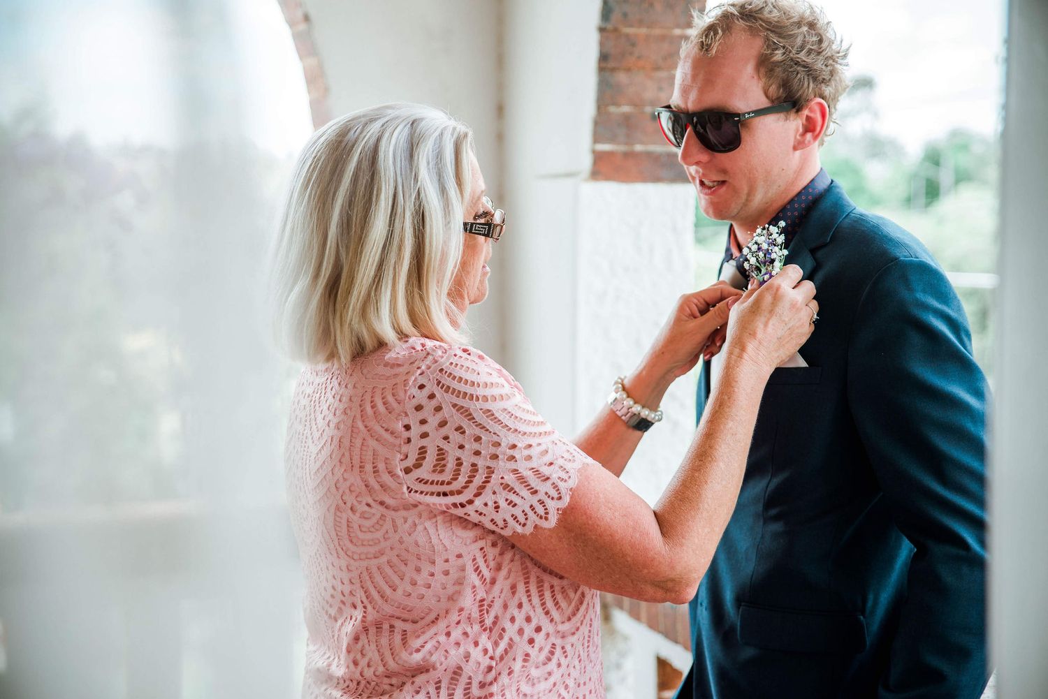 Someone adjusting a navy suit tie in bright natural lighting.