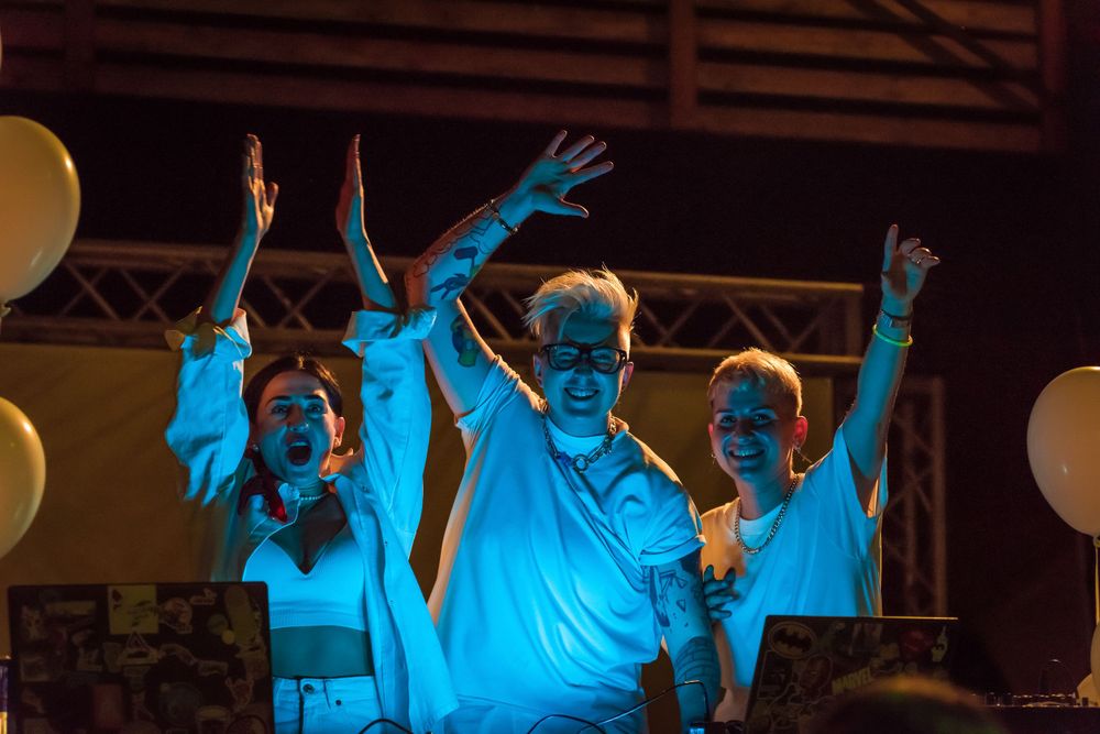 Group of performers with raised arms illuminated by blue stage lighting.