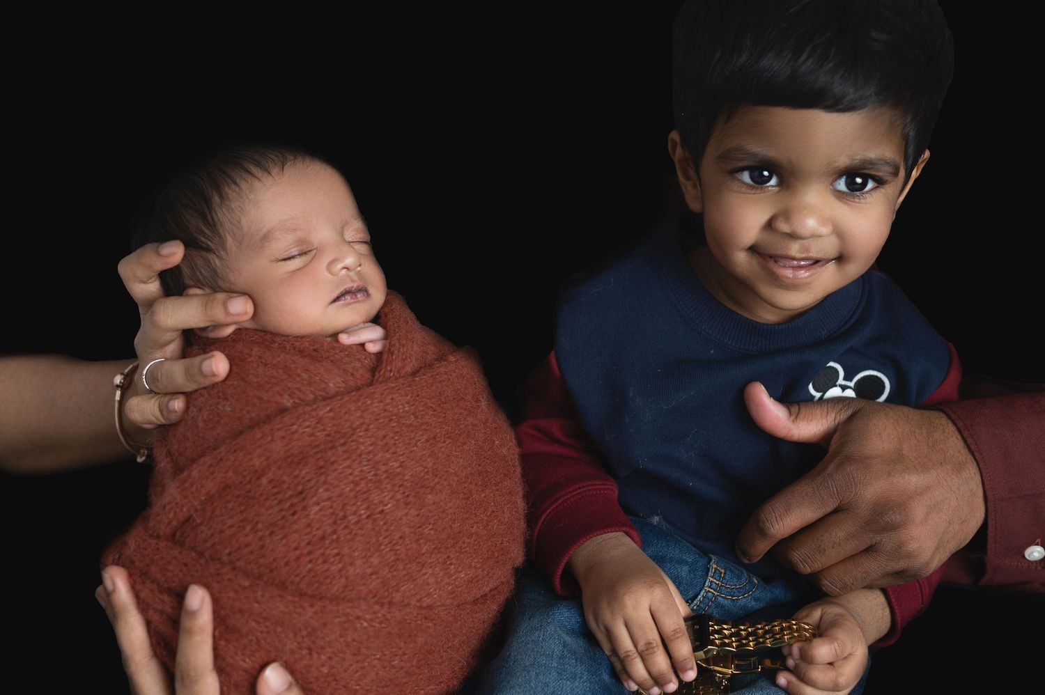 A sweet family portrait showing a sleeping newborn and toddler sibling.