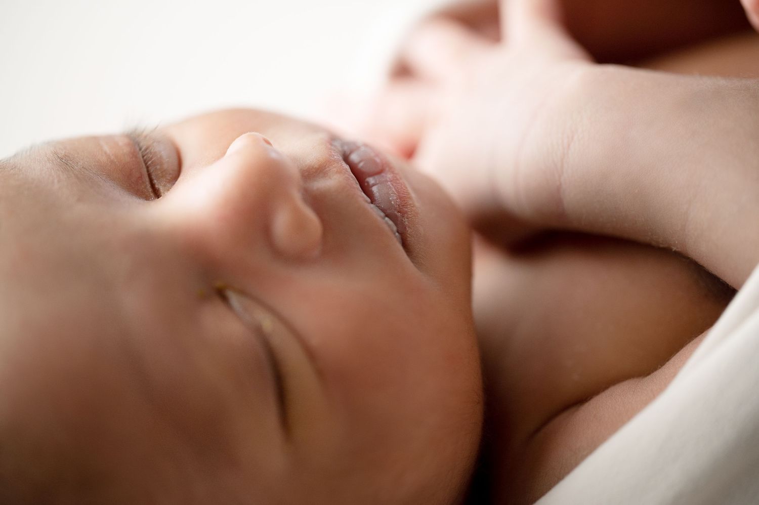 Close-up portrait of a sleeping newborn baby with peaceful expression in soft lighting.