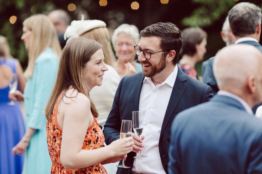 Wedding guests socializing at dusk with bokeh lights in the background.