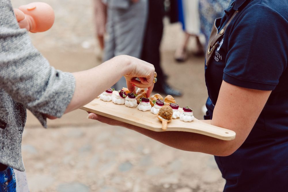 Guests mingling and sharing food at an elegant outdoor wedding reception.