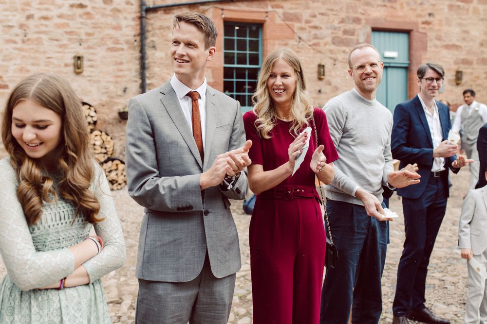 Wedding party members in formal attire celebrating outside a historic venue.