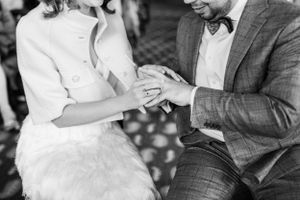 Black and white photo of couple's hands during ring exchange ceremony.