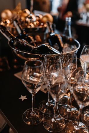 Elegant wine glasses and champagne bottles arranged on dark table for wedding reception.