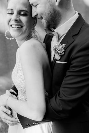 Intimate black and white portrait of newlyweds sharing a tender moment in formal attire.
