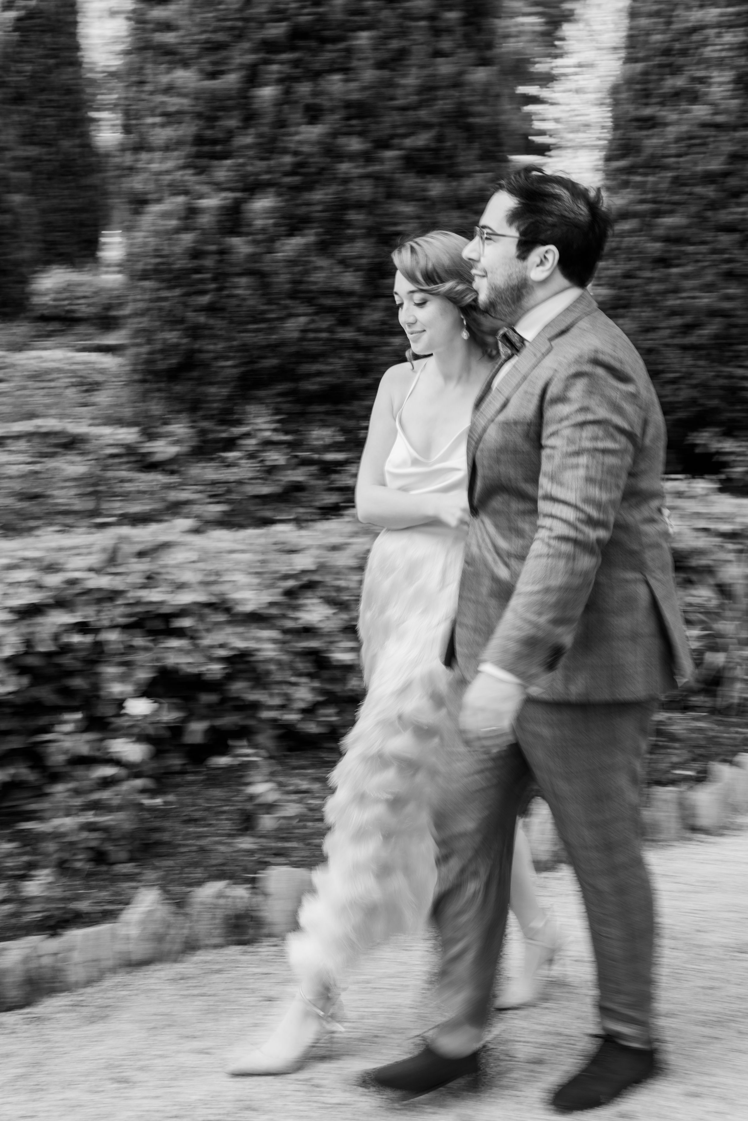 Black and white photo of couple walking together in formal attire.