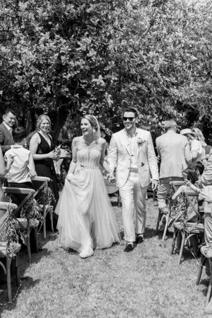 Wedding recessional through garden with guests seated on either side of aisle.