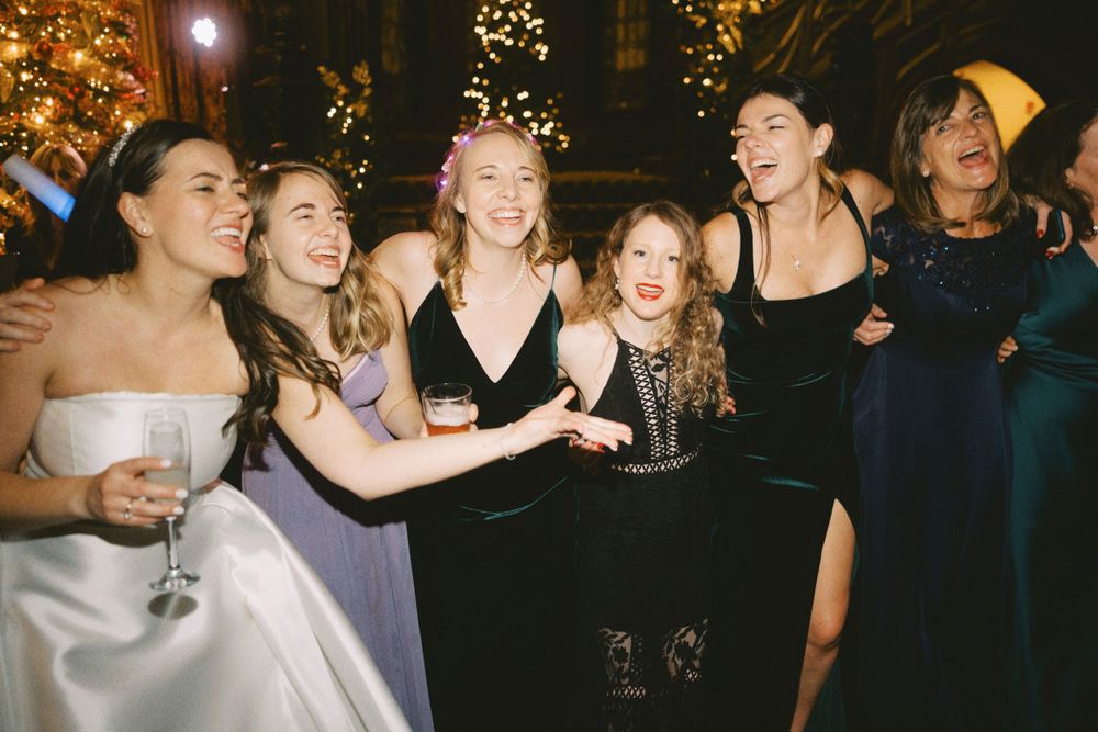 Wedding guests dance and celebrate during a lively reception with festive lighting and decor.