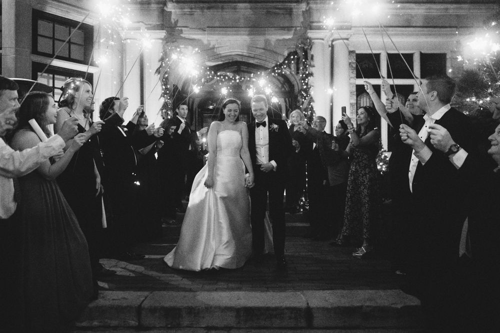 Elegant wedding reception with guests holding sparklers creating a glowing tunnel effect.