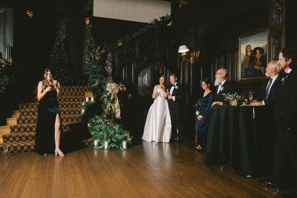 Formal wedding celebration with guests in elegant attire gathered in a wood-paneled venue.