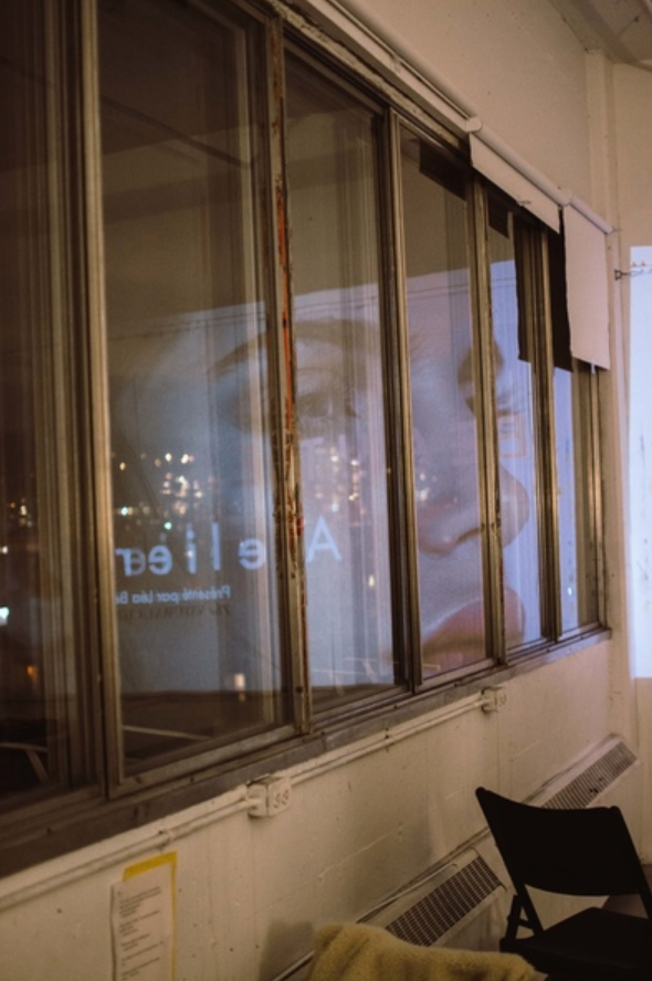 A window display at night showing reflective glass panels with soft lighting in the background.