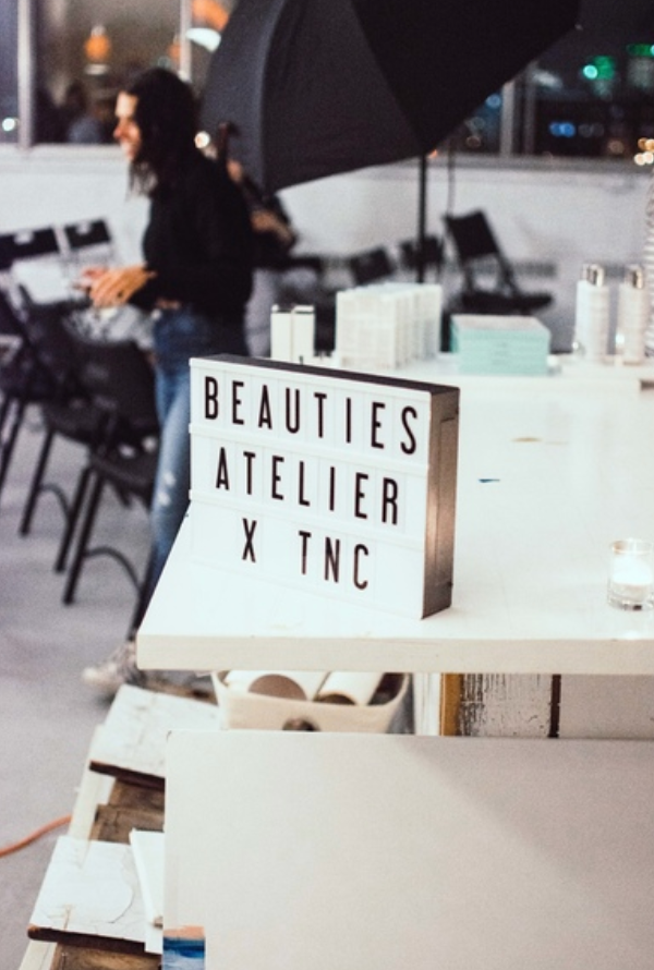 A beauty atelier workspace with signage and professional equipment set up on white tables.