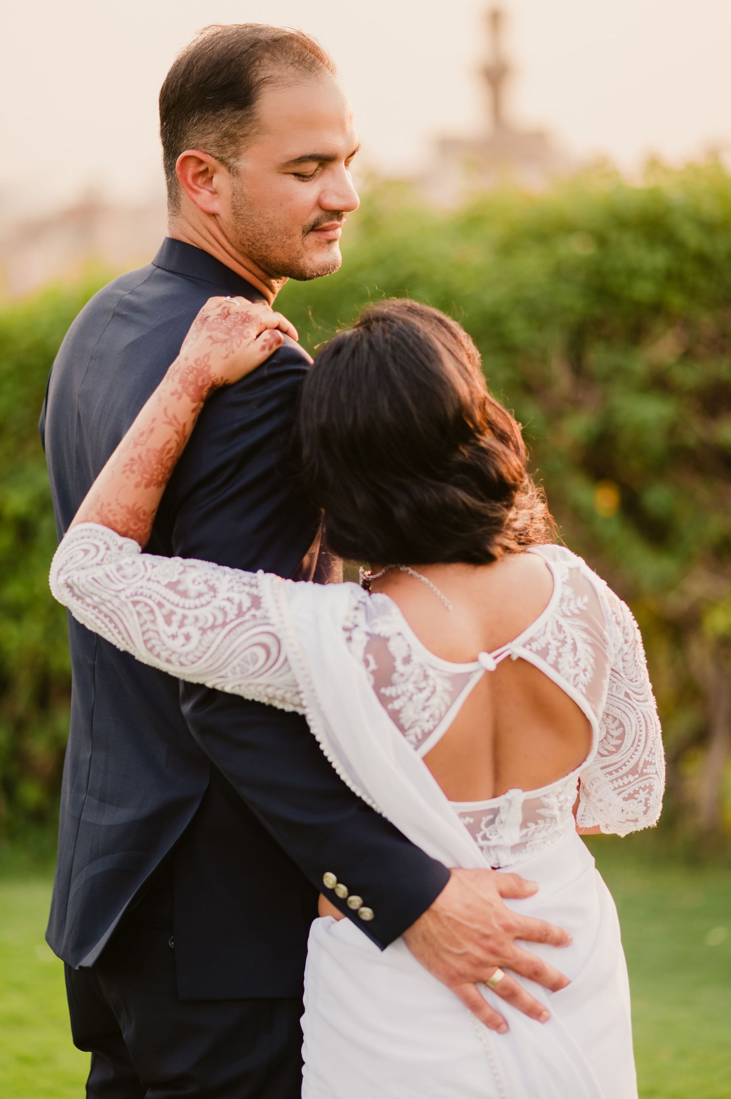 A detailed back view of an elegant lace wedding dress as the couple shares an intimate moment.