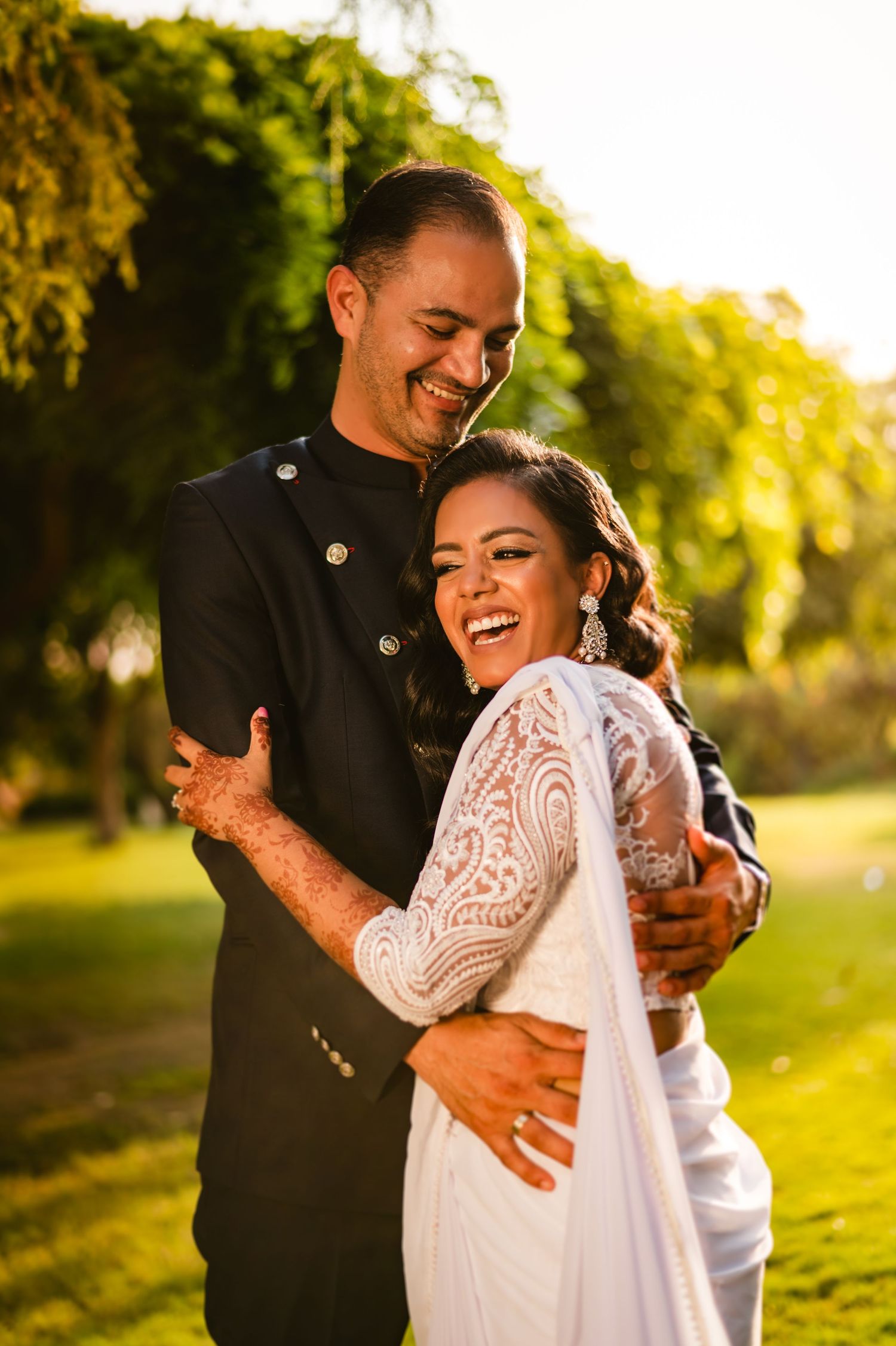 A joyful wedding moment captured in natural sunlight with the couple laughing together.