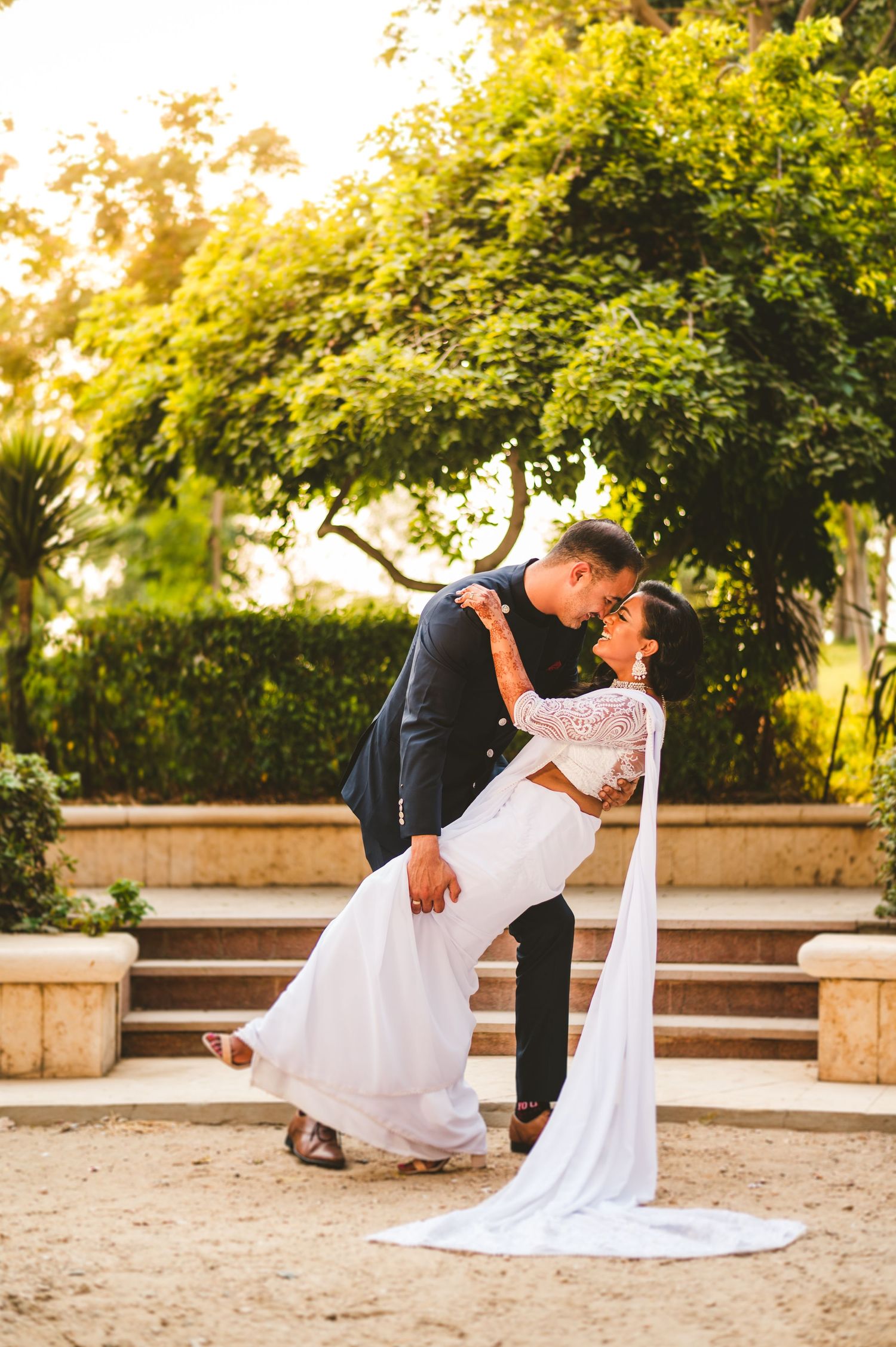 A romantic wedding dip pose with a flowing white dress against a garden backdrop at golden hour.