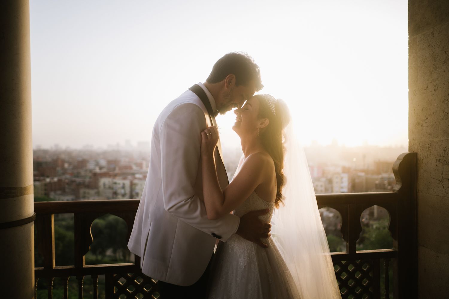 A romantic sunset embrace on a balcony overlooking the city.