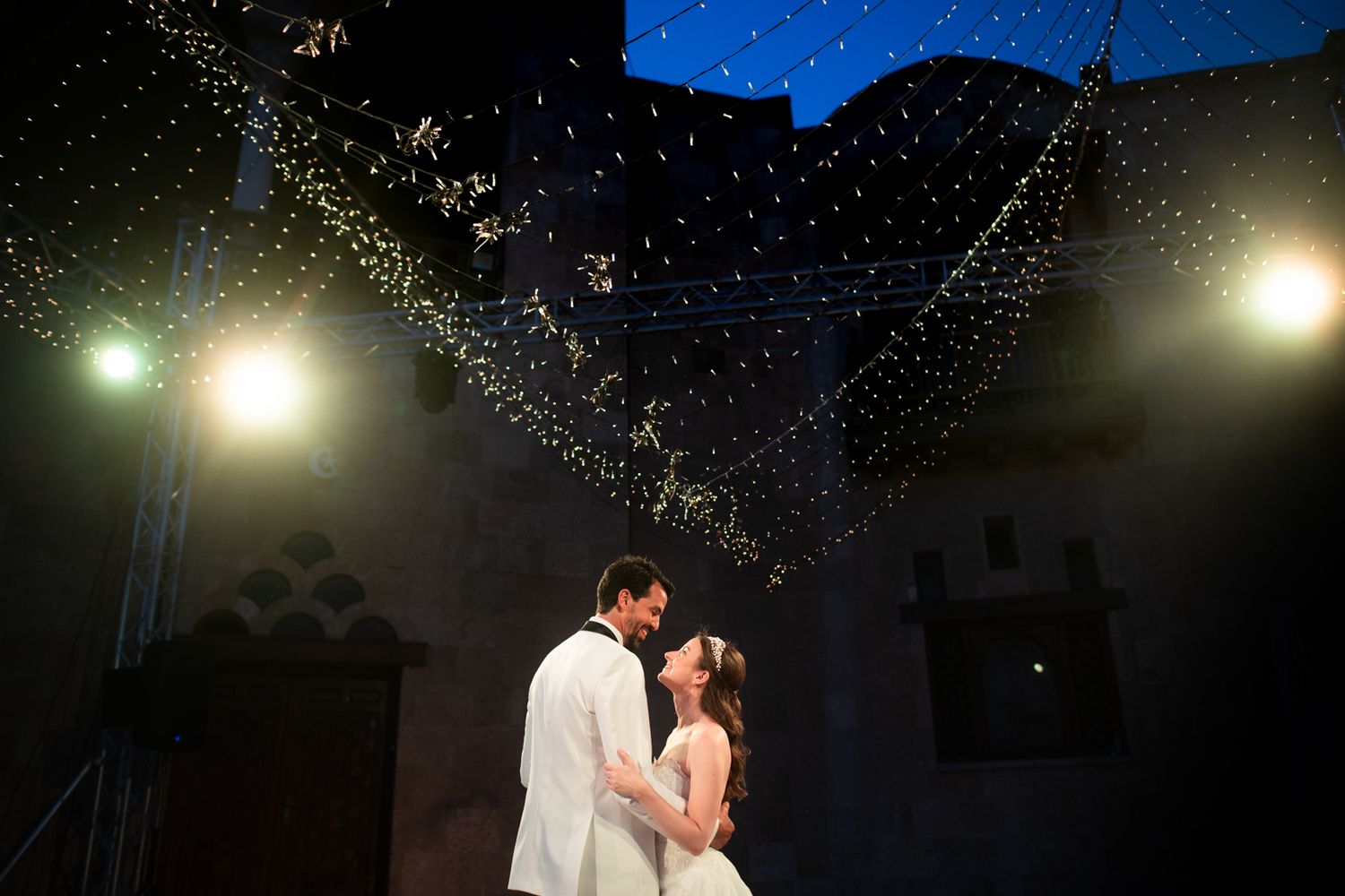 A couple shares their first dance beneath a canopy of sparkling lights.