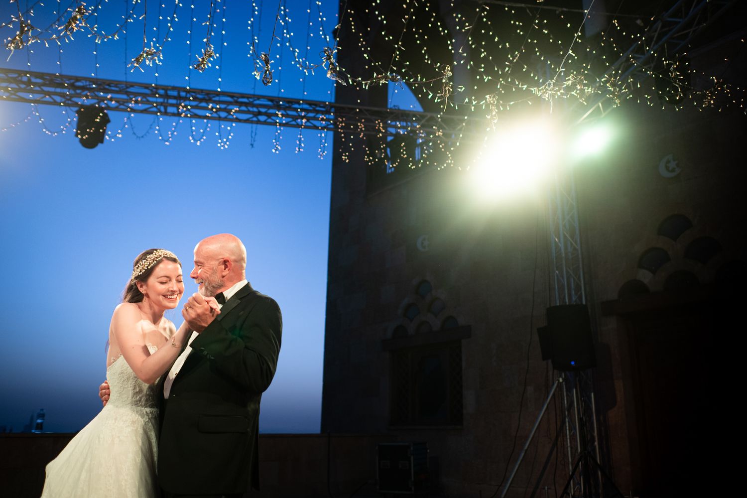 A romantic moment under string lights against a dramatic blue and black backdrop.