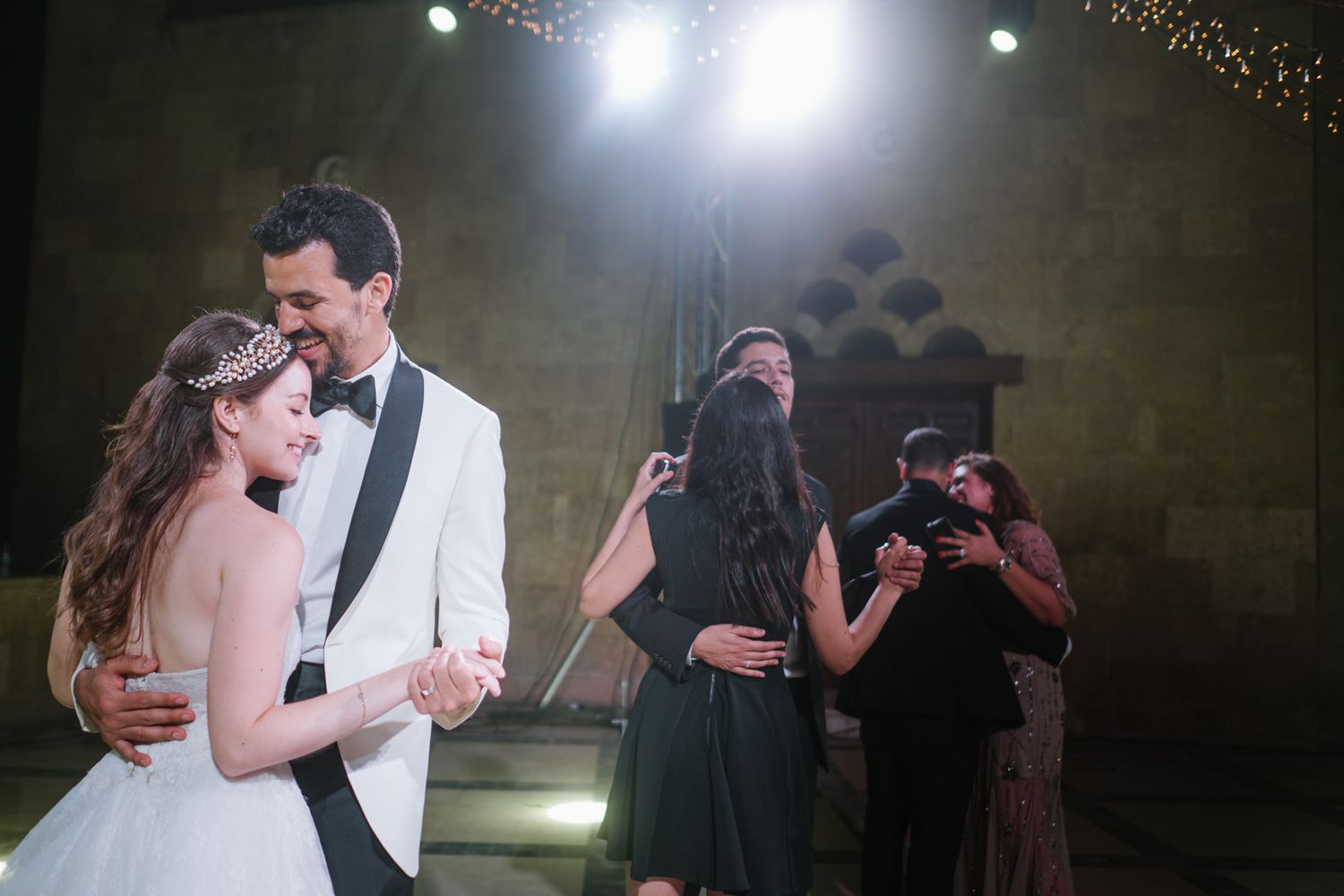 Wedding reception dance floor with couple in foreground and photographers in background.