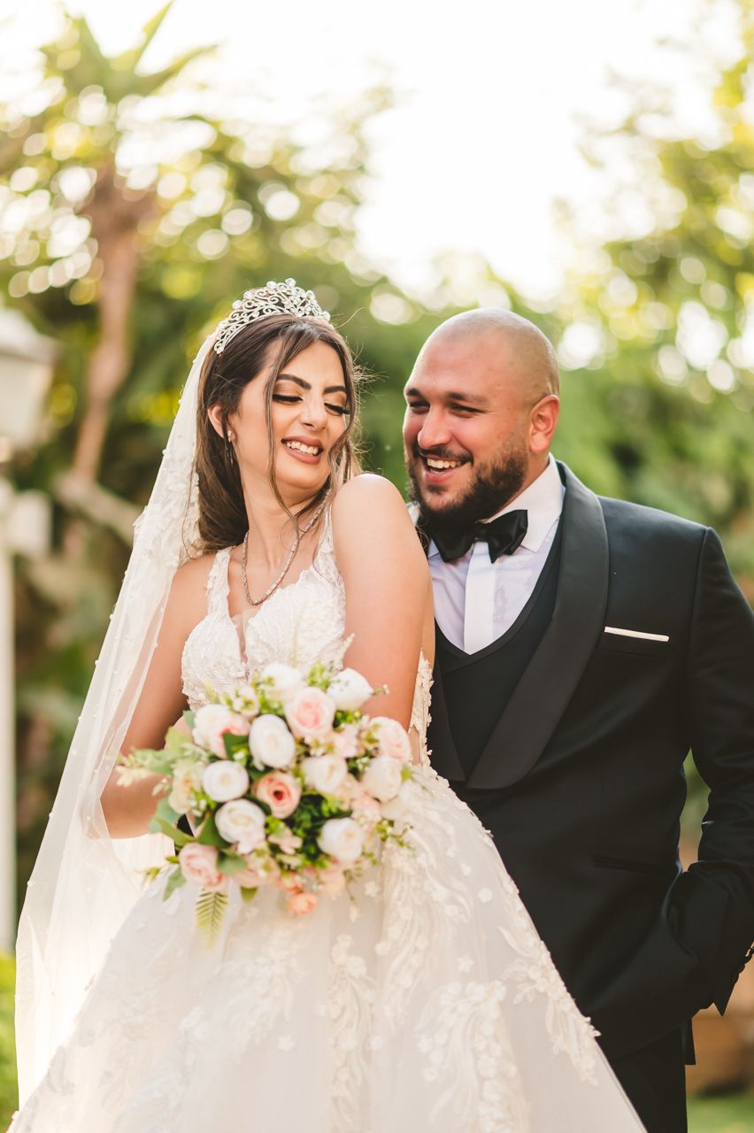 A romantic wedding portrait outdoors with bride wearing tiara and holding pink bouquet.