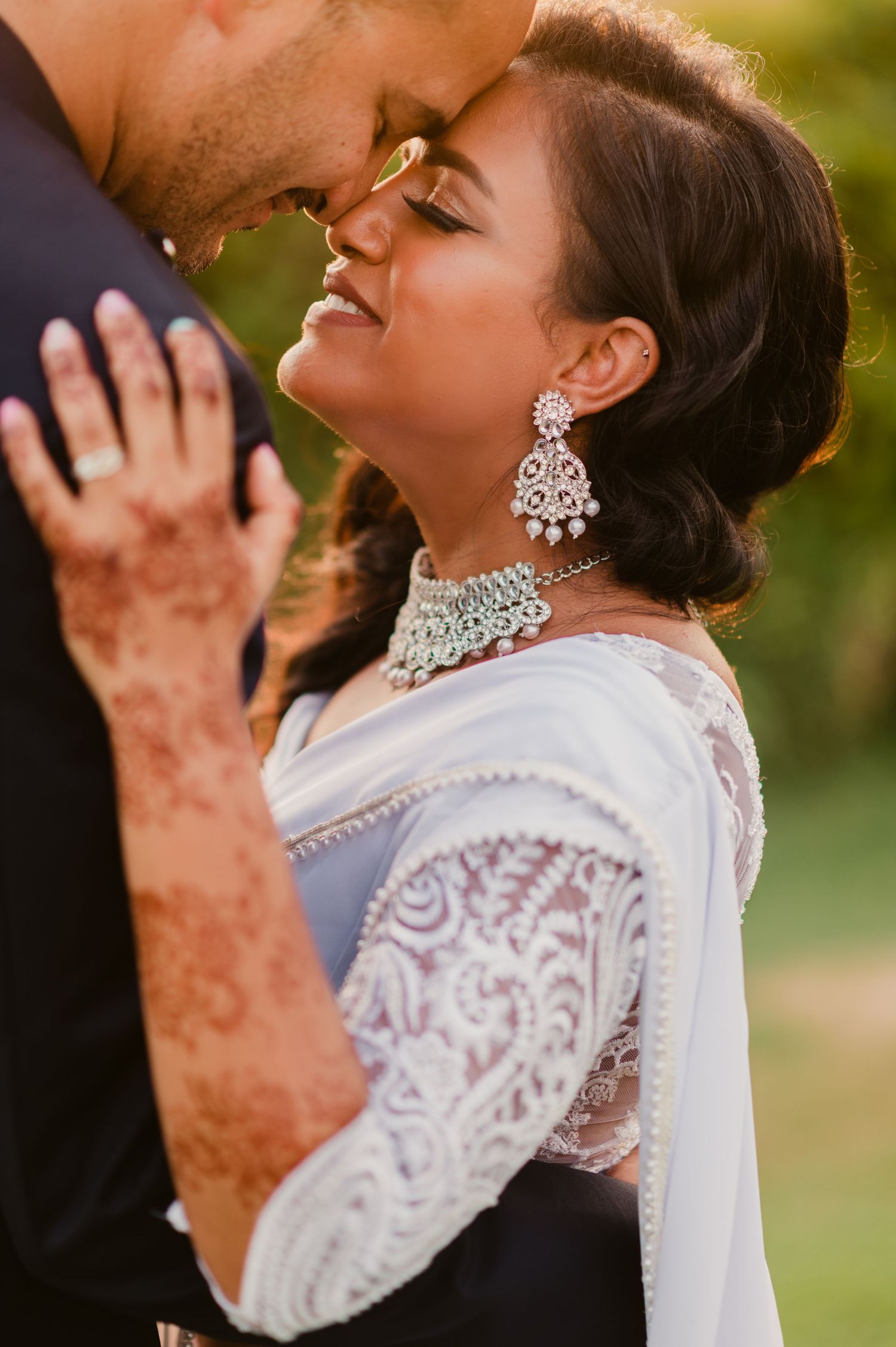 A romantic wedding moment with the bride wearing elegant Indian jewelry and traditional henna designs.