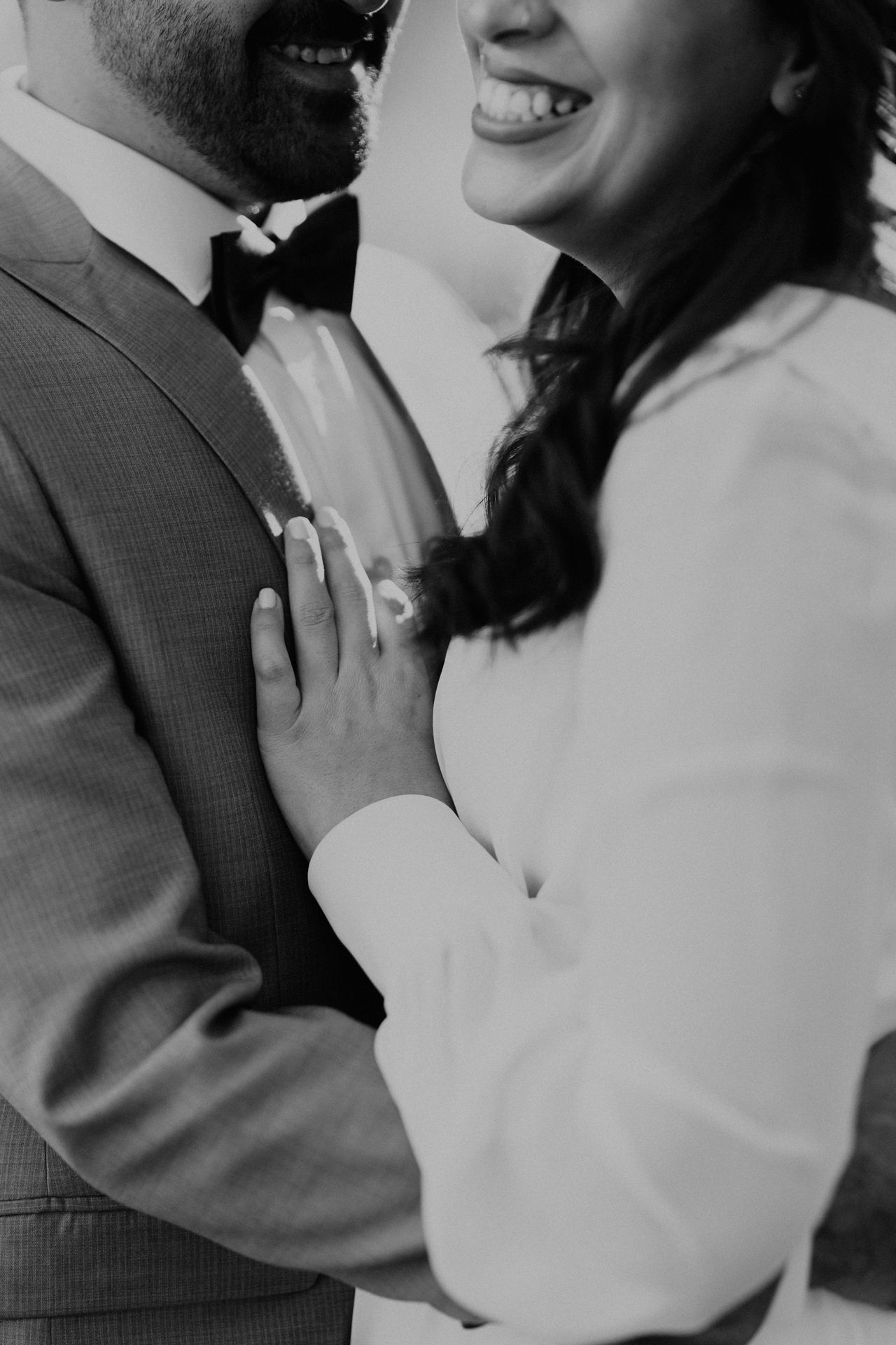 Black and white close-up of happy couple sharing intimate moment in formal attire.