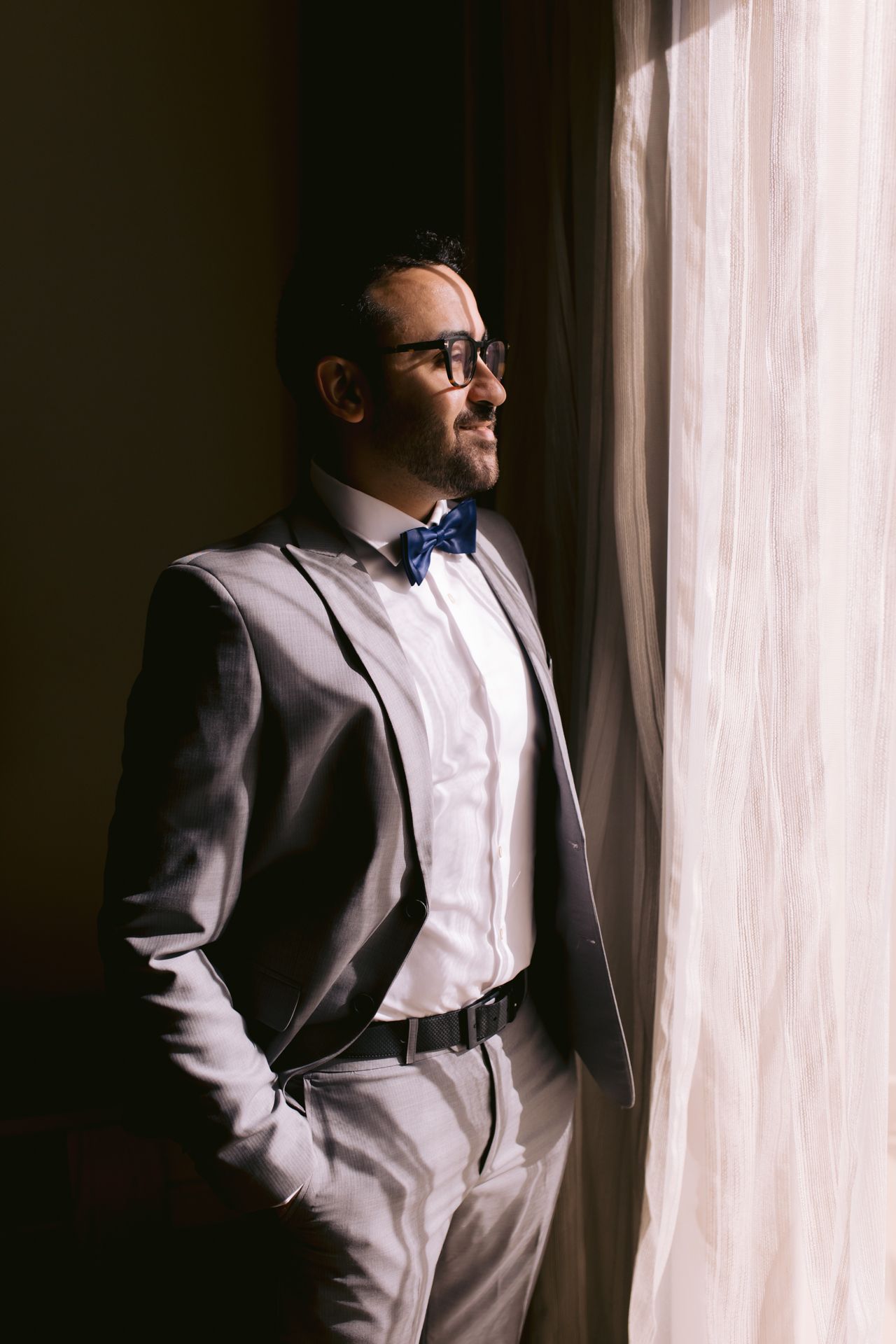 Side profile of person in formal wear gazing thoughtfully out window.