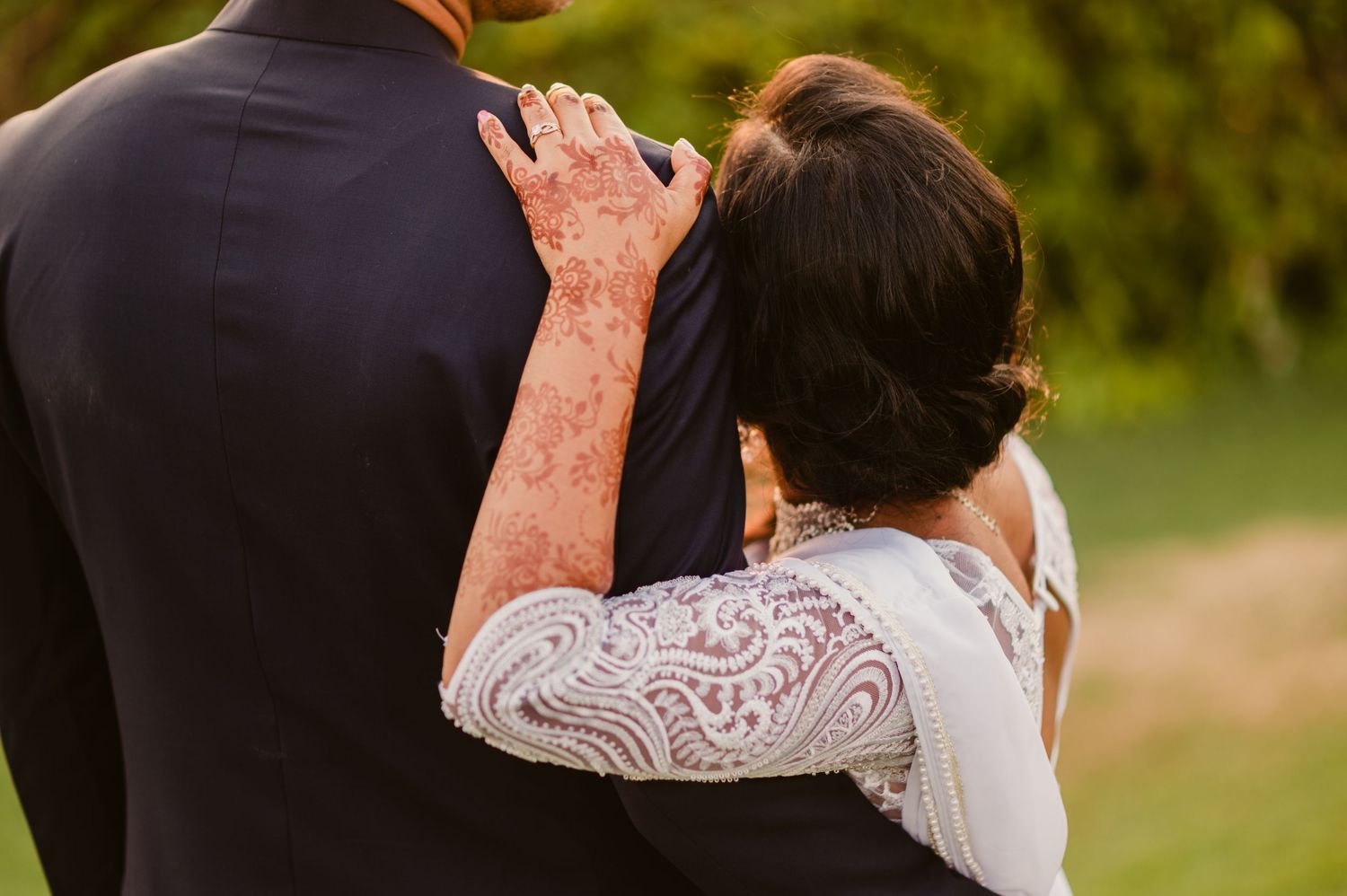 A close embrace between bride and groom showing traditional mehndi henna designs during a wedding celebration.