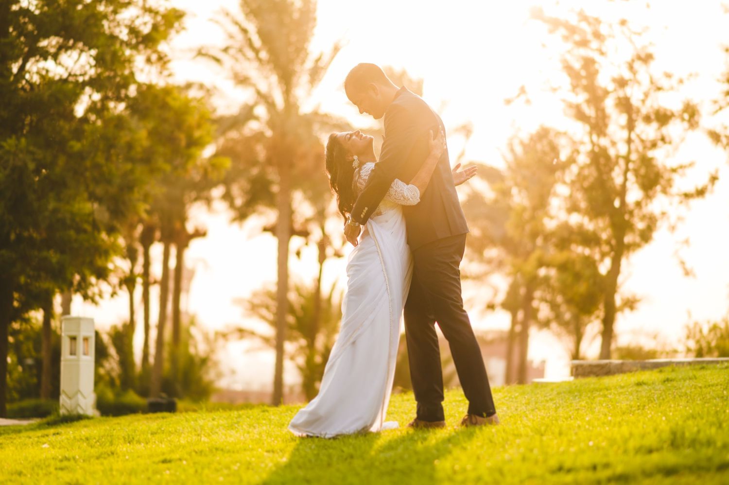 A romantic sunset wedding photo with silhouettes dancing on a grassy hill.