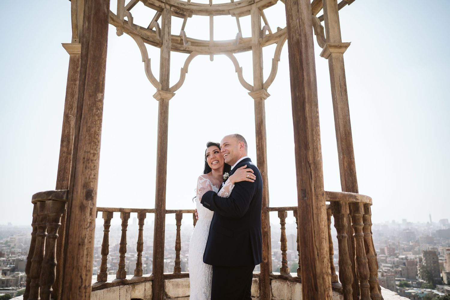 A couple shares an intimate moment in a vintage architectural overlook above the city.