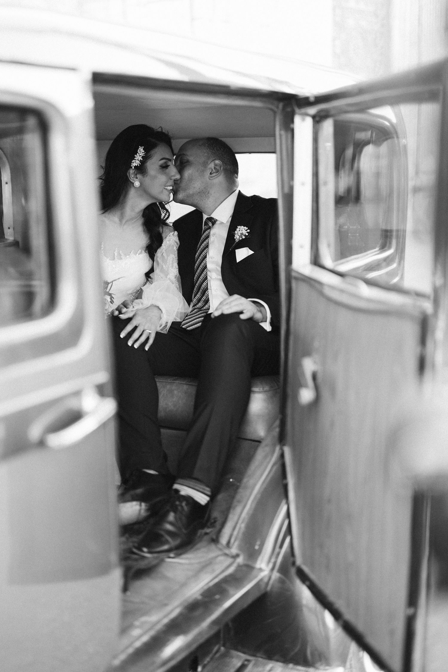 Intimate black and white photo of wedding couple inside vintage car.