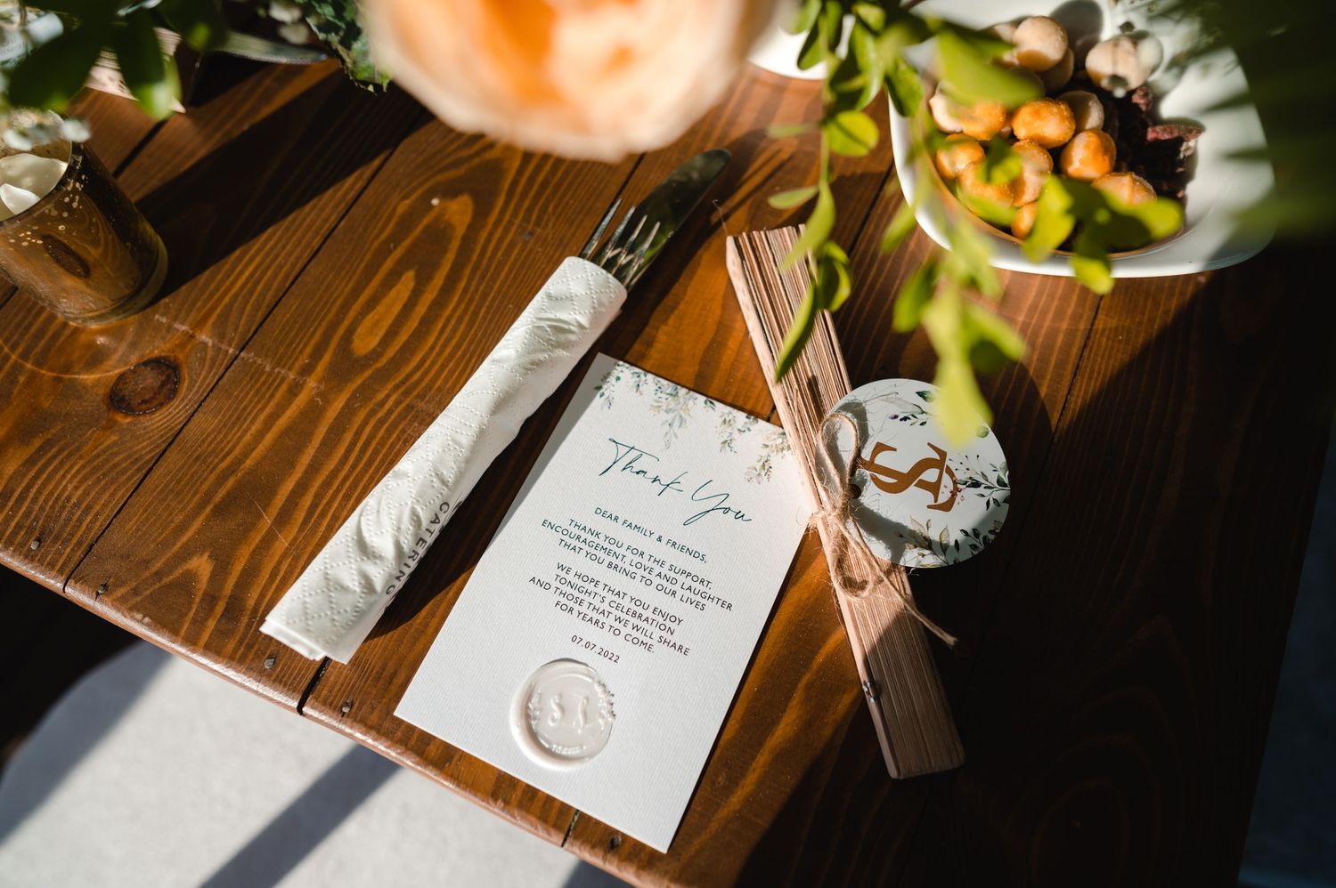 Wedding menu and wine glass on wooden table with natural lighting.