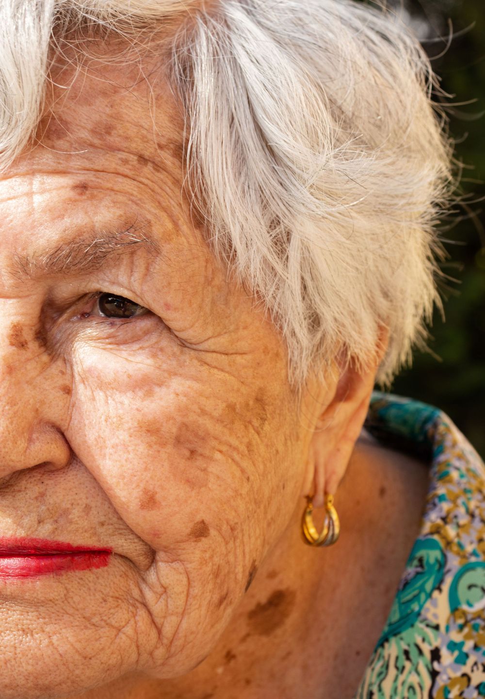 Elderly person with silver hair and floral print clothing in profile.