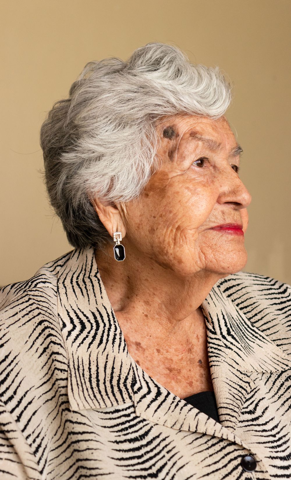 An elderly person wearing a zebra print top poses in a series of artistic profile shots.