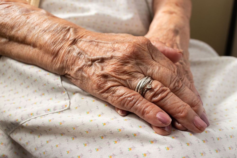 Close-up shots of aged hands resting on a textured surface.