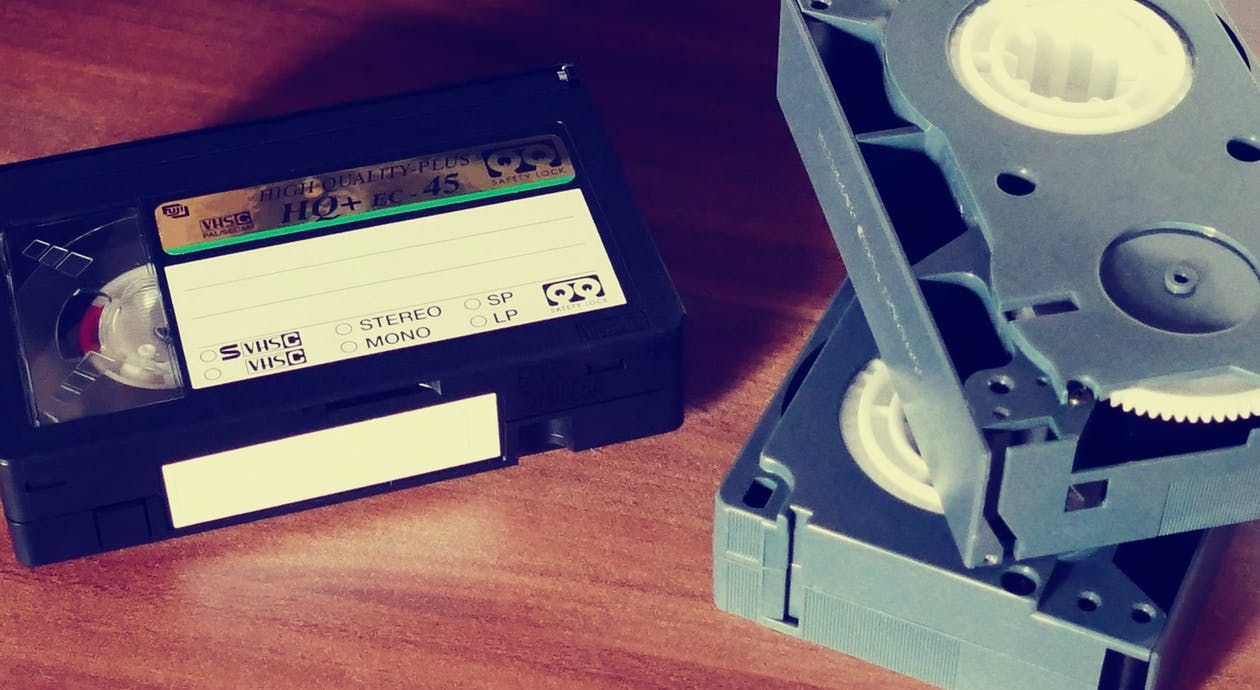 Vintage VHS tapes and video cassettes on wooden surface with retro filter effect.