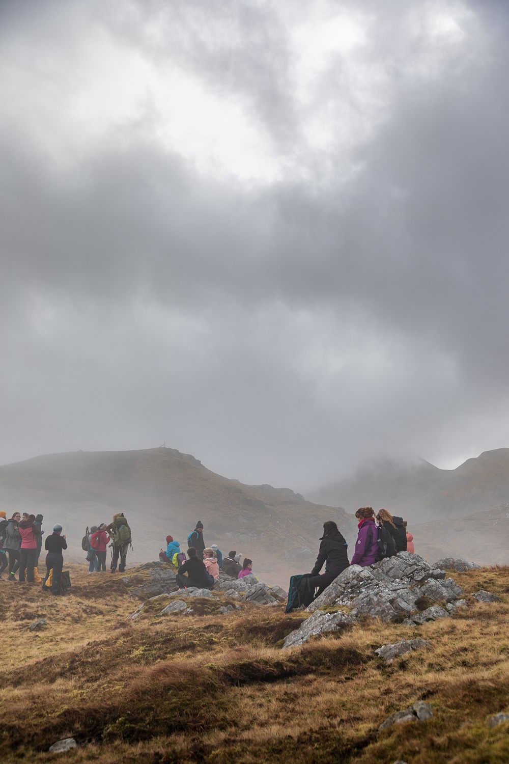 a group of woman sitting on some rocks, having lunch during their hike to Ben Baun in Connemara national park