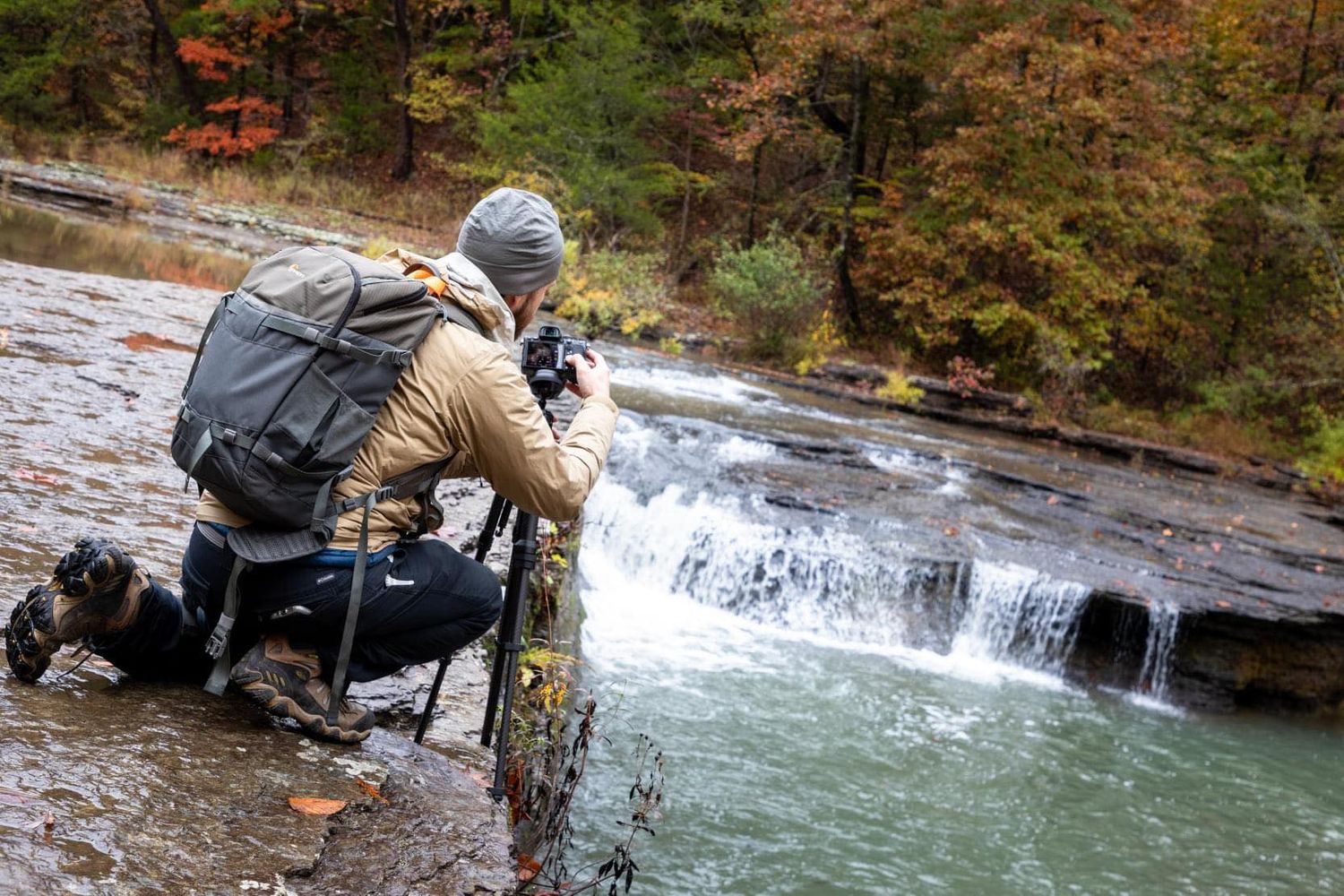 Arkansas nature photographer, Alex Kent on knees photographing Haw Creek falls with camera on tripod.