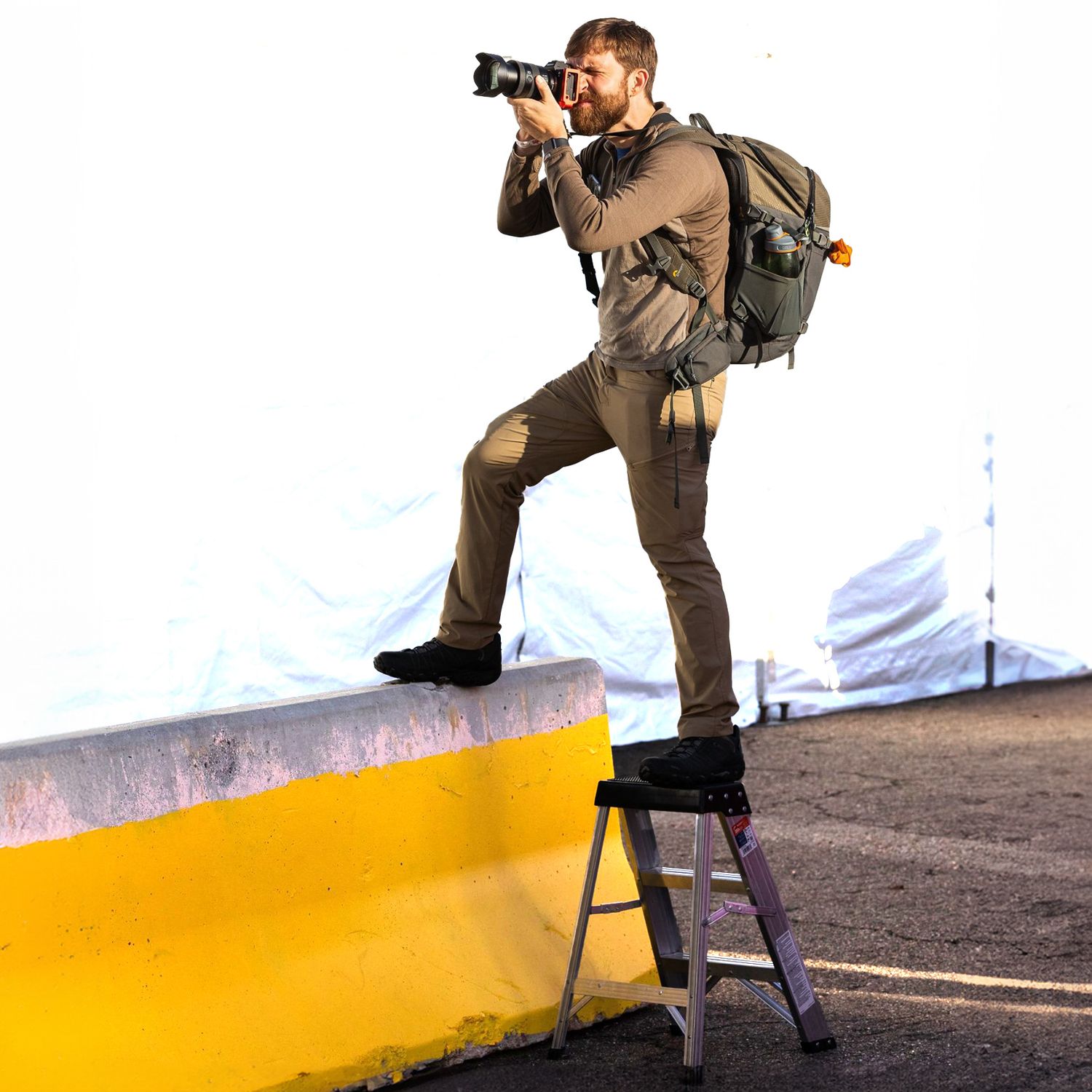 Arkansas nature photographer, Alex Kent standing on a concrete barrier holding a camera with telephoto lens up to eye