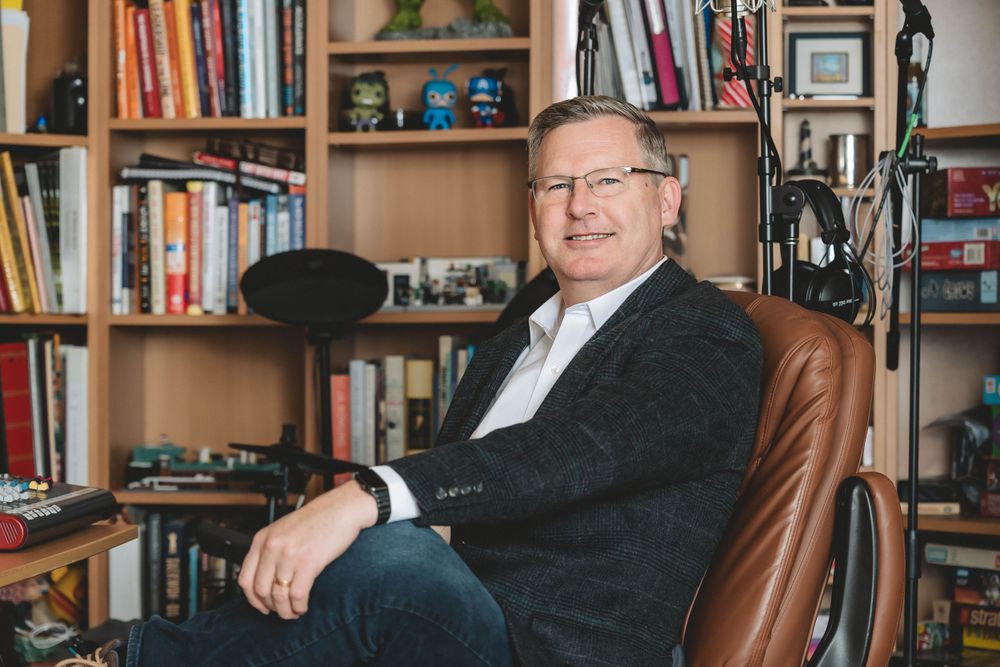 Person sitting in leather chair in home office with bookshelves and decor in background.