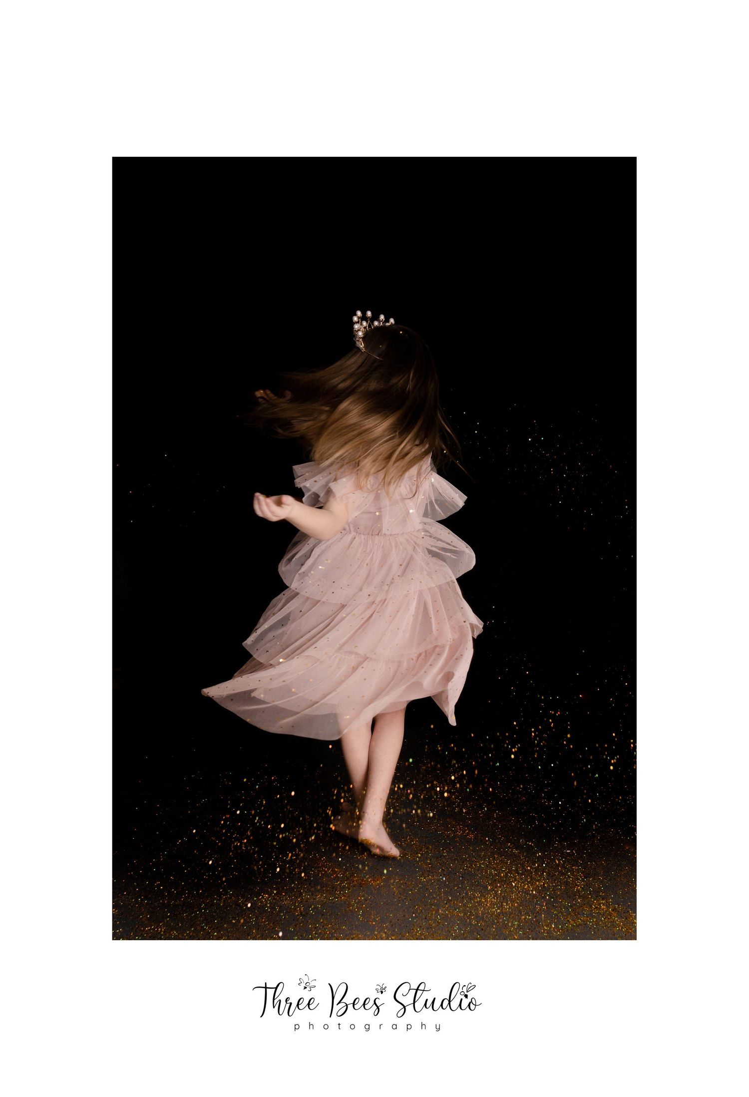 A twirling figure in a pink tulle dress against a dark background with golden glitter.