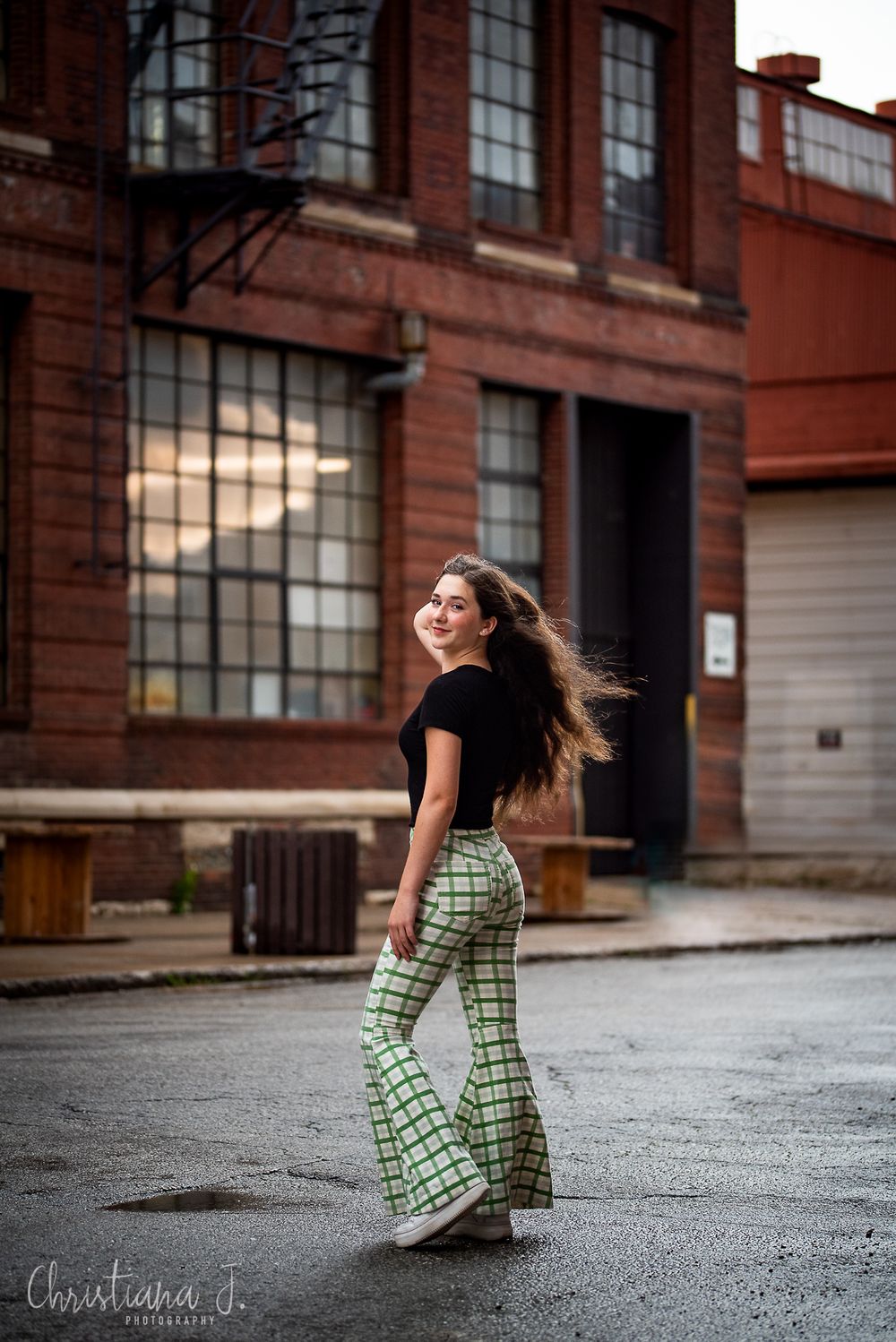 Candid street style photo in retro flared pants and black top against brick building.