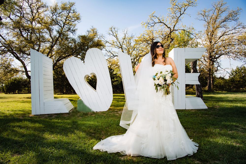 Wedding portrait with large white LOVE letters display in outdoor garden setting.