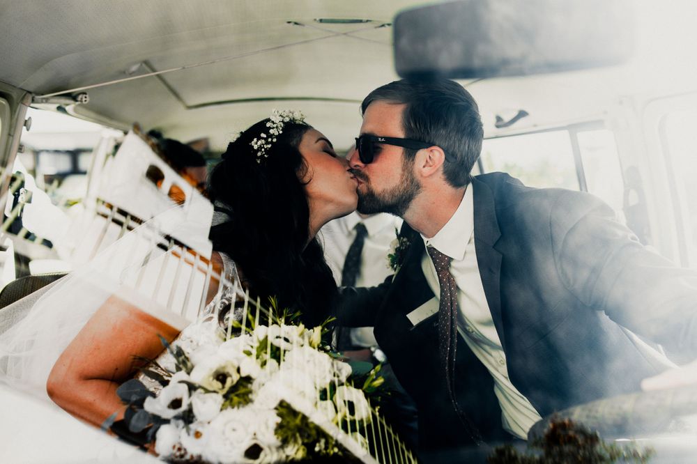 bride and groom first kiss inside volkswagon van