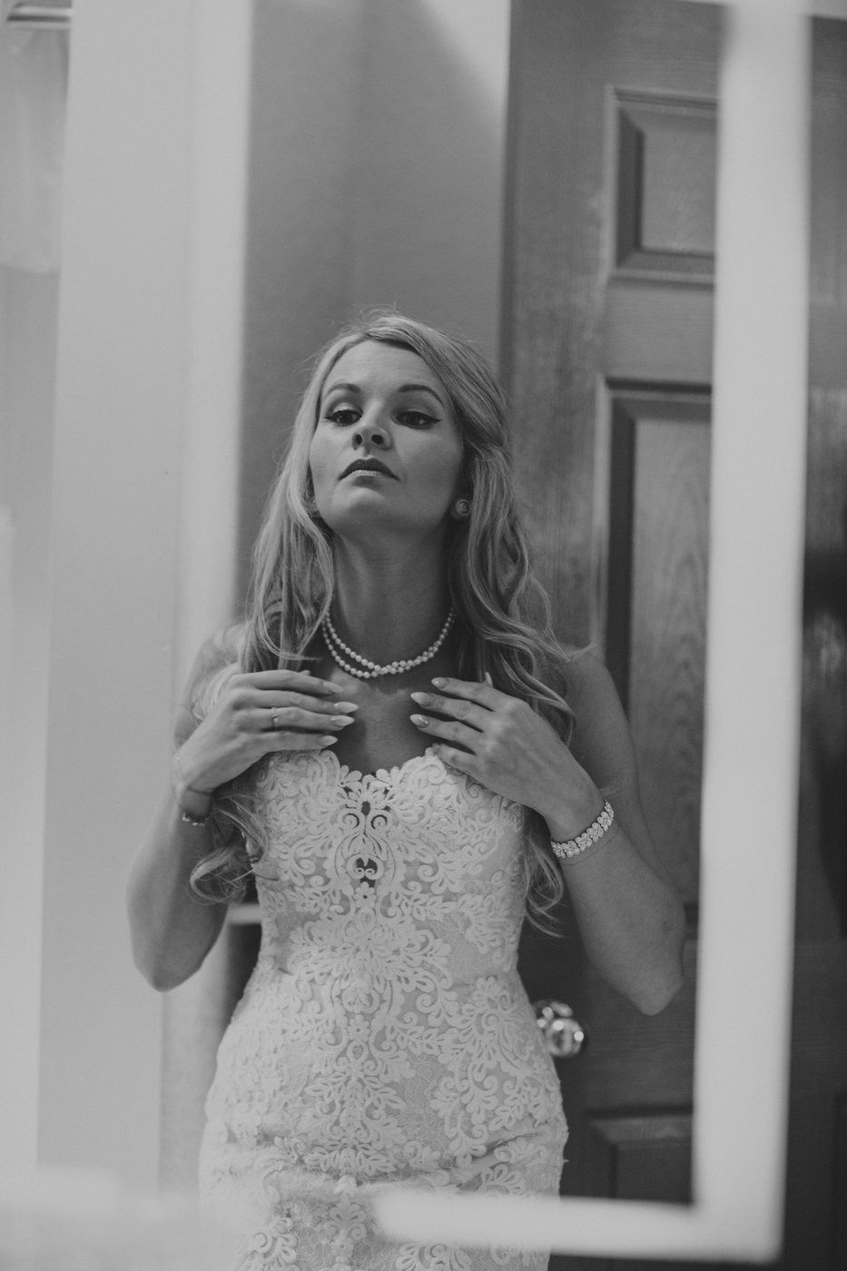 Classic black and white bridal portrait showcasing elegant lace dress and pearl necklace.